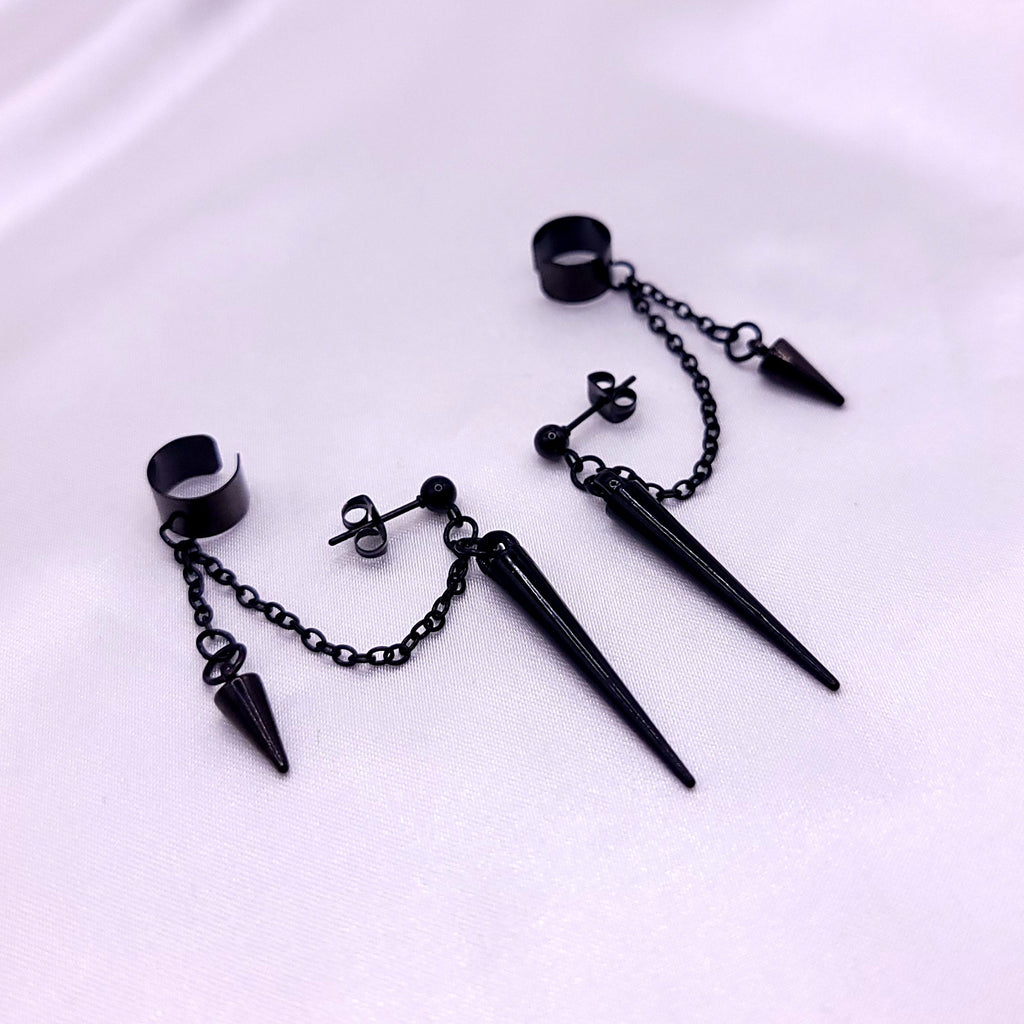 Black spike earrings on a white fabric background