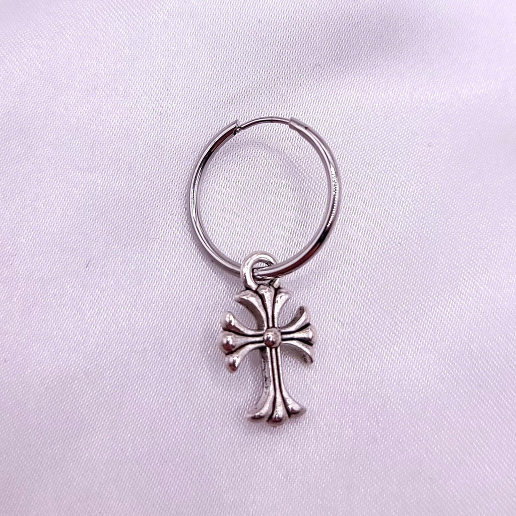 Single silver hoop earrings with cross on a white fabric background
